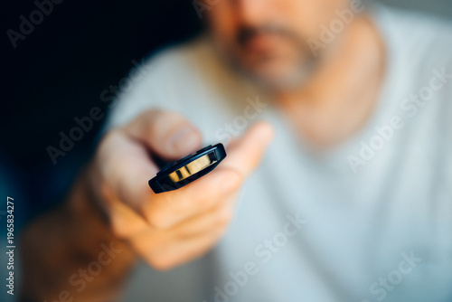 Εκτύπωση καμβά Close-up of man holding TV remote control with selective focus on buttons and fi