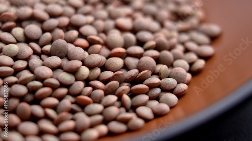 Raw brown lentils in wooden dish. Organic legume ingredient. Macro. Rotation