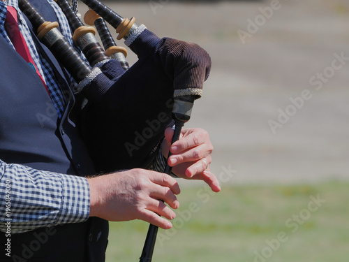 Man playing bagpipes in Scottish band marching at highland games. 