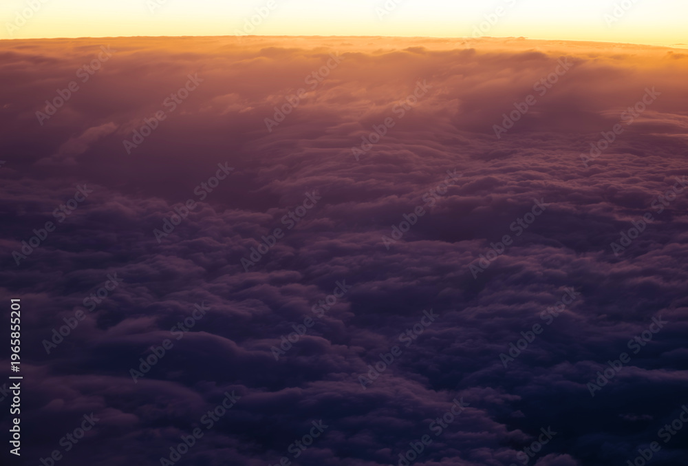 Fototapeta premium a high-altitude aerial view of a dense, fluffy cloudscape during a sunrise