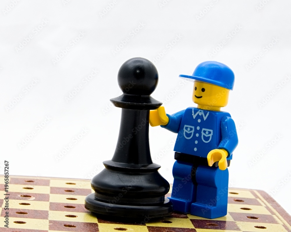Fototapeta premium A lego figurine with a chess piece on a small chess board