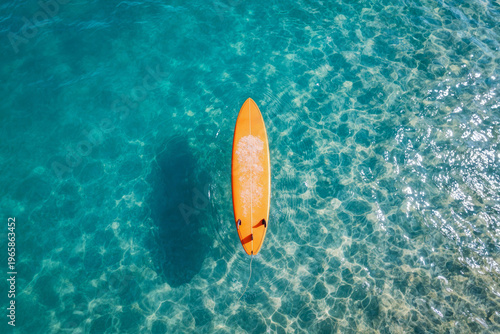 Surfboard aerial top view orange floating in the clean and clear sea water wave