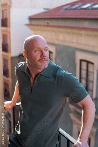 Confident mature man standing on balcony in city at sunset, urban lifestyle portrait