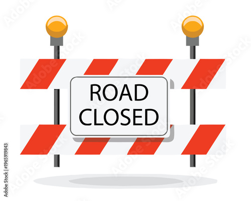 A road closed sign on a barricade with traffic lights on a street