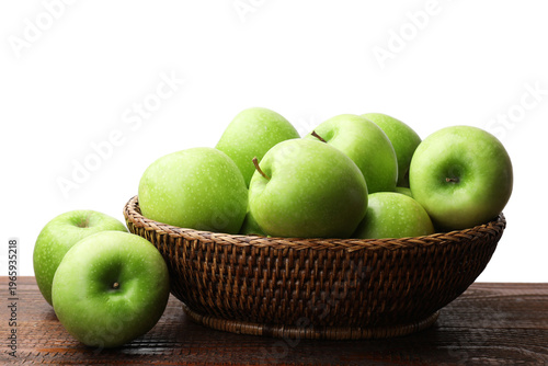 Fresh ripe green apples in wicker basket on wooden table against white background