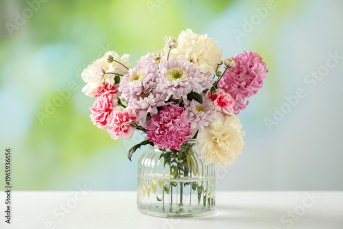 Bouquet of beautiful flowers in vase on white table against blurred background