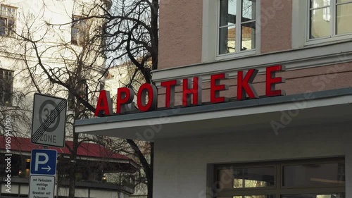Pharmacy sign reading Apotheke on a building facade in Bogenhausen, Munich, Germany. Urban street scene with local healthcare service in a typical European residential district. Apotheke in Muenchen
