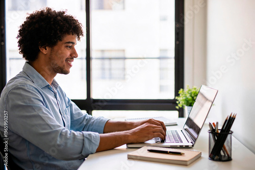 Homem trabalhando em home office com laptop em ambiente iluminado e organizado