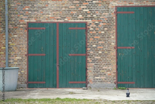 a former brick horse stable with two green wooden doors