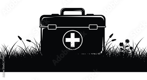A black silhouette of a medical kit with a medical cross rests in tall grass evoking themes of health and aid silhouette