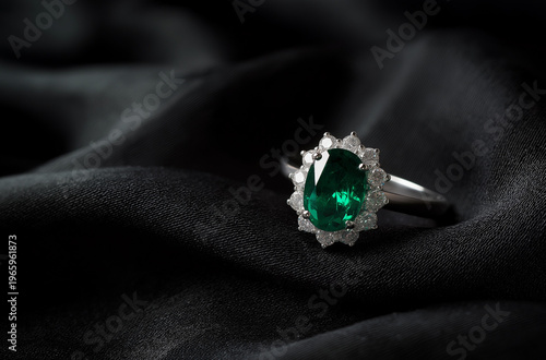 A luxurious emerald ring with diamonds on a black fabric background