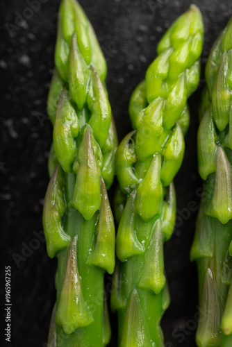 Gourmet macro shot of fresh blanched asparagus spears on dark slate background. Healthy spring vegetable with dramatic lighting.