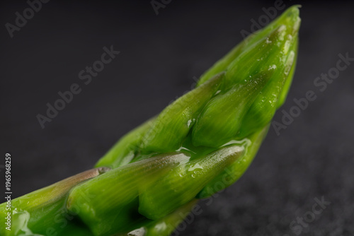 Gourmet macro shot of fresh blanched asparagus spears on dark slate background. Healthy spring vegetable with dramatic lighting.
