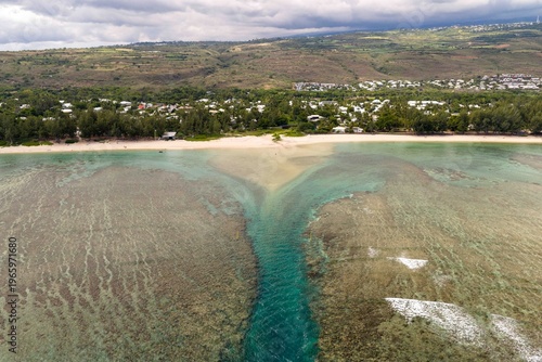defaultAerial drone view of La Saline-les-Bains lagoon and coastline under cloudy sky.
