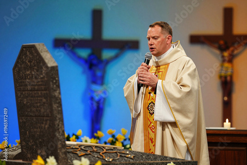 Man in a priest's robe speaking into a microphone.