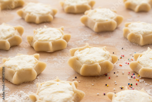 Process of making traditional Italian ricotta cheese pastries on wooden board with flour and colorful sprinkles