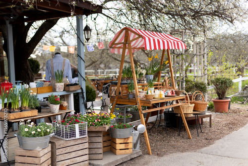 Wallpaper Mural Cozy outdoor garden shop with blooming plants in pots and seasonal holiday display. Easter exterior market stall with spring flowers, wicker baskets, bunny shaped candles, and festive decorations.  Torontodigital.ca