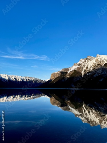 Cuadro en lienzo Panoramic mountain range reflected in calm lake under blue sky