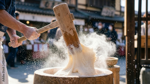 Person pounding mochi with a wooden mallet in a Japanese street setting