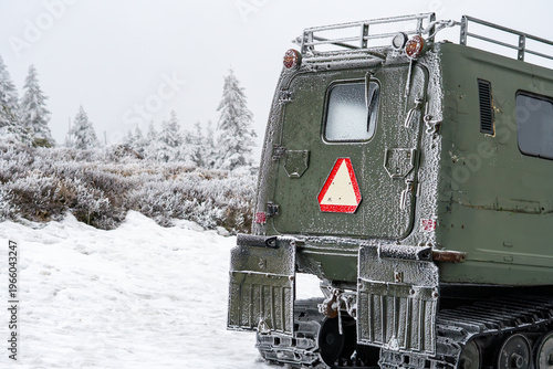Military tracked vehicle in winter mountains, snowcat transporter covered in frost, heavy duty off-road machine in arctic conditions, mountain rescue equipment, winter expedition, caterpillar tracks o
