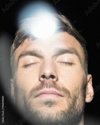 Man with closed eyes and radiant light from above
