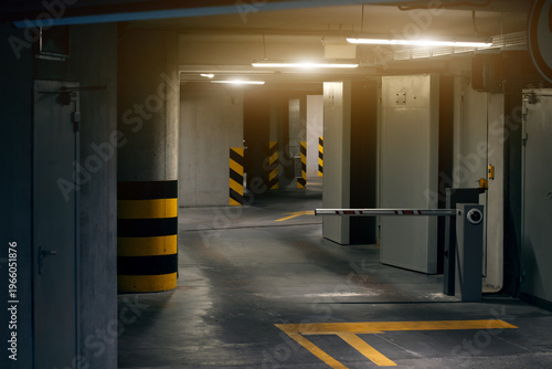 A dimly lit parking garage with a barrier arm and yellow markings on the floor and pillars