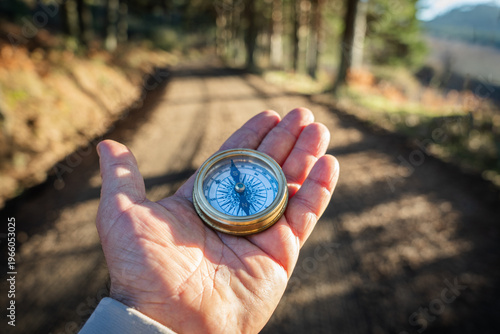 Obraz na plátne Human hand holding compass on forest track guiding future direction, navigation,