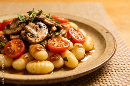 Gnocchi mit gebratenen Champignons und frischen Tomaten in aromatischer Sauce stilvoll serviert