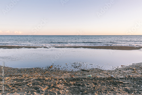 Polluted beach shoreline with litter and ocean waves