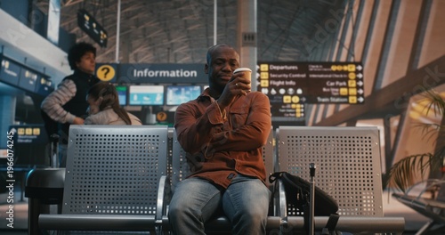 Foto Young Black Man Arrives at Airport Waiting Area, Sets Down Luggage, Immediately Checks Smartphone