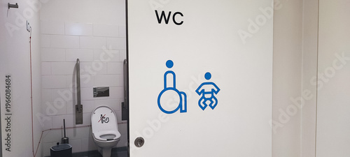 An accessible public restroom with wheelchair and baby changing symbols on the door and safety grab bars inside. Concepts of inclusivity, accessibility, and modern public infrastructure design.