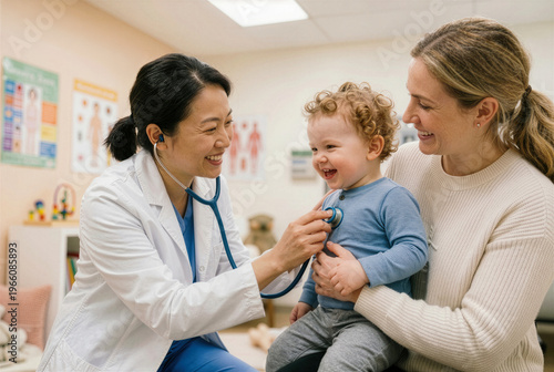 Asian female doctor examining happy toddler in pediatric clinic