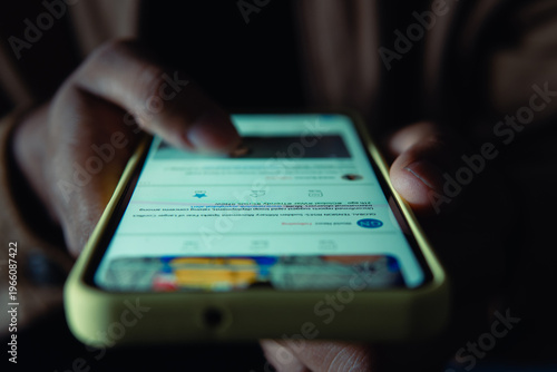 Person scrolling news feed on digital device at night