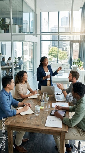 Team brainstorming meeting in a modern office, a team of individuals gathered around a table engaged in a productive discussion