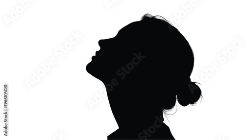 Profile silhouette of a young woman looking upwards with her hair gathered in a bun against a bright.