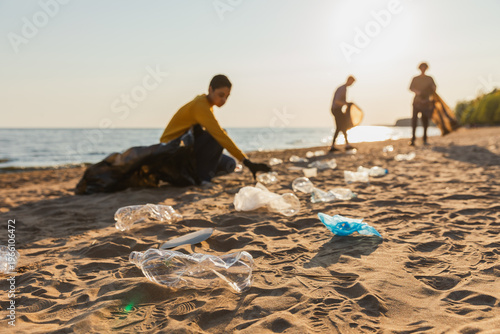 Earth day. Volunteers activists collects garbage cleaning of beach coastal zone. Woman mans with trash in garbage bag on ocean shore. Environmental conservation coastal zone cleaning. Blurred image