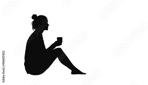 Woman silhouette sits sideways holding a small mug while relaxing during a break on a white surface.