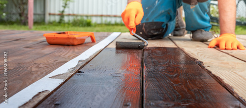 Wallpaper Mural Worker applies dark finish to wooden deck surface Torontodigital.ca
