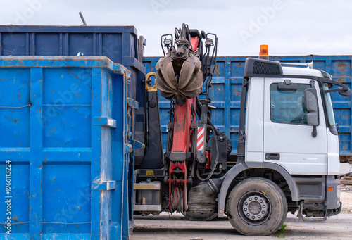 Canvas Print Industrial truck with boom crane and material handler grapple moving blue skip c