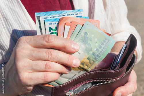 Leather wallet and euro banknotes in a woman's hands, selective focus.	