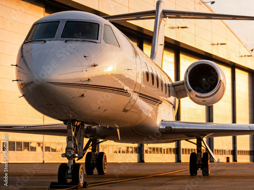 Zakelijke Jet Positioned Close To Hangar At Sunset With Glowing Reflective Surfaces And Readiness Appearance
