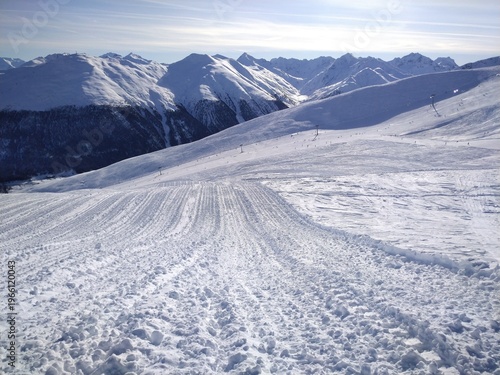 New groomed slope. Track lines on a ski slope left by a snowcat . Snow groomer track. A view of snow - covered mountains in winter and a ski lift in Norway.