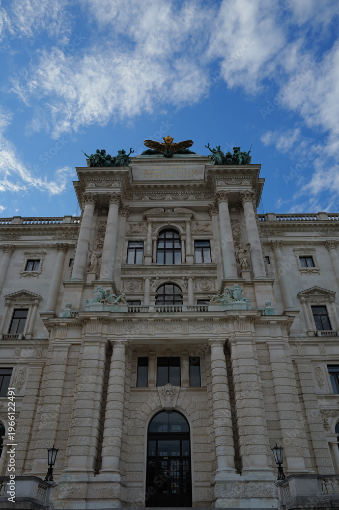 Fototapeta premium Grand ornate European classical building facade with columns and arches against blue sky