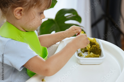 Cute little girl eating broccoli, vegetables for children as a source of vitamins, healthy lifestyle, vegetarian