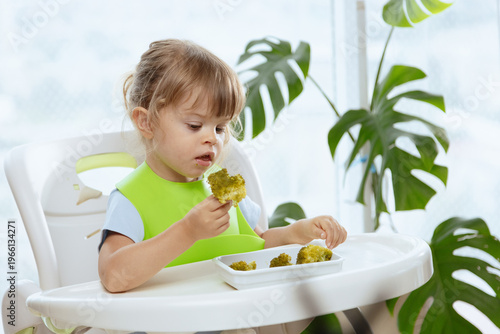Cute little girl eating broccoli, vegetables for children as a source of vitamins, healthy lifestyle, vegetarian