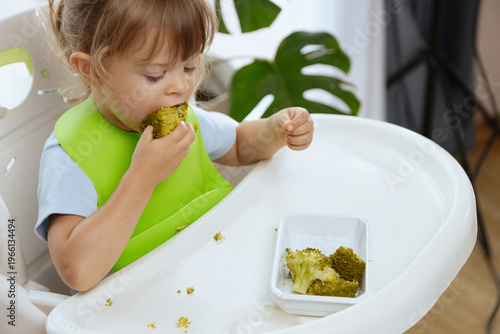 Cute little girl eating broccoli, vegetables for children as a source of vitamins, healthy lifestyle, vegetarian