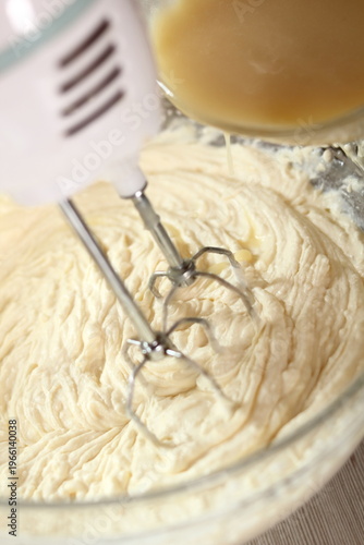 Pouring white chocolate and butter mixture into cheese filling. Making frozen strawberry cheesecake series.