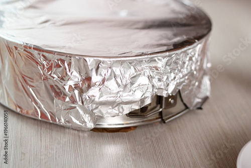 Covering baking pan with foil before and place to fridge. Making frozen strawberry cheesecake series.