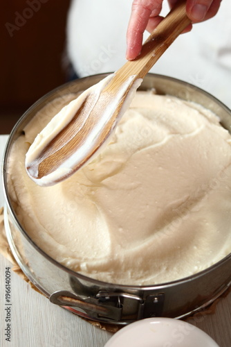 Leveling batter by spoon. Making frozen strawberry cheesecake series.