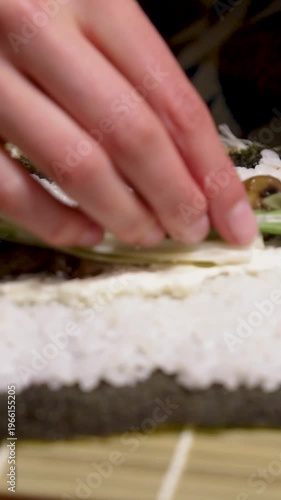 Sushi homemade adding spring onion stripes to sushi roll with mushrooms fresh cheese and rice vertical